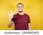 Russian man wearing basic red t-shirt over yellow insolated background showing and pointing up with fingers number four while smiling confident and happy.