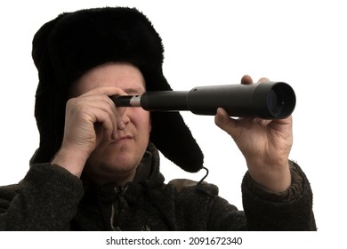 A Russian Man Wearing A Fluffy Hat, Looking Through A Hand Held Telescope On A White Background. 