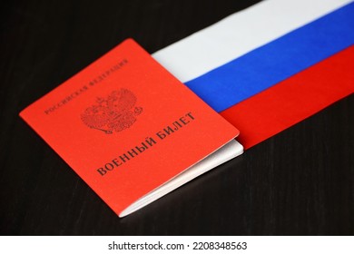 Russian Military ID And National Flag On Wooden Table. Translation Of Inscription: Military ID Card, Russian Federation. Concept Of Mobilization In Russia