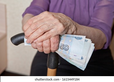 Russian Money In The Hand Of An Elderly Woman With A Cane. Pension And Disability.