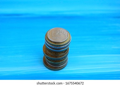 Russian one ruble and a stack of gold coins on a blue background - Shutterstock ID 1675540672