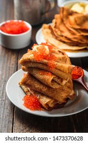 Russian pancakes blini with red caviar on wooden background