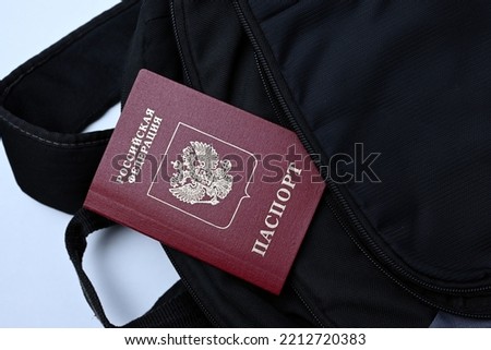 Russian passport in a black backpack. Young men fleeing mobilization and leaving Russia in a rush with light baggage