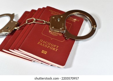 Russian Passport And Handcuffs On A White Background. Prohibition Of Russian Citizens On Entry And Exit. Passport Lock