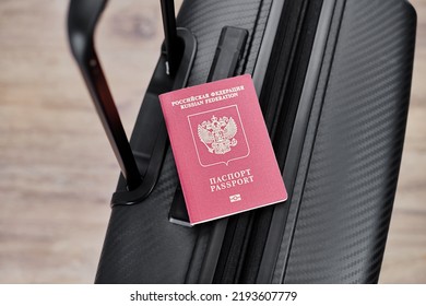 Russian Passport On A Black Travel Suitcase, Top View, Selective Background. Emigration Of Russians, Seeking Asylum