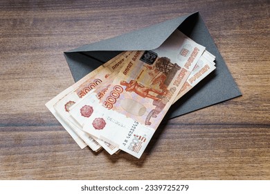 Russian rouble banknotes and gray envelope on table closeup