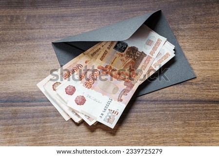 Russian rouble banknotes and gray envelope on table closeup