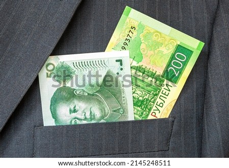 Russian roubles and Chinese yuan in businessman suit pocket. Money in the pocket of business suit. Worldwide currencies