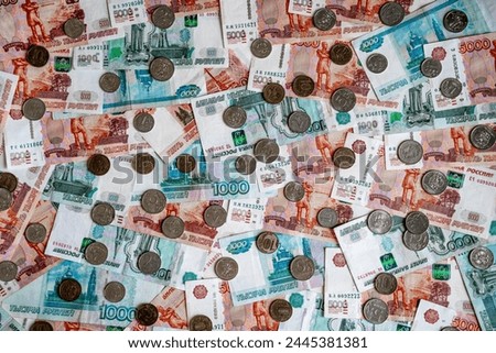 Russian ruble bills with a denomination of one thousand rubles, a denomination of five thousand Russian rubles and small change coins of one ruble, two rubles, ten rubles cover the entire background