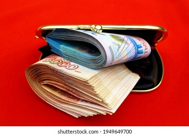 Russian rubles bills in a red open wallet. The denomination of the banknotes is two 2000 and five 5000 thousand rubles.