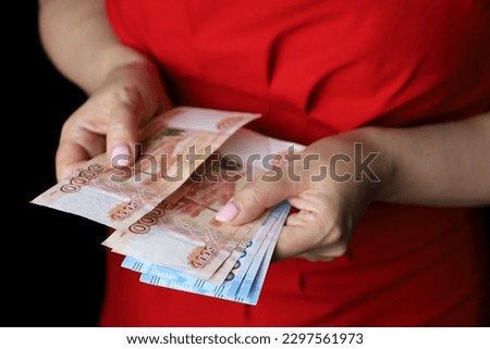 Russian rubles in female hands, cash pay, salary, inflation or savings concept. Woman in red dress counting paper currency of Russia