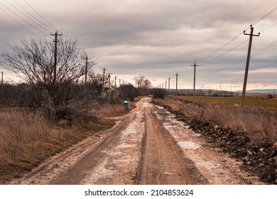 Russian rural dirt road in late autumn on a cloudy day after rains. Dirty track and puddles, poor traffic.