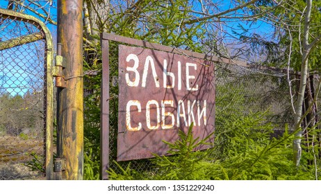 A russian sign on the steel fence of the property saying vicious dogs in russian language
