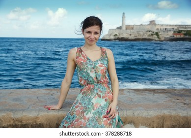 Russian skinny girl in a green dress on the Havana waterfront