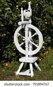 Russian Spinning Wheel Is Painted White. In The Apple Orchard.