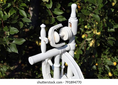 Russian Spinning Wheel Is Painted White. In The Apple Orchard.