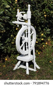 Russian Spinning Wheel Is Painted White. In The Apple Orchard.