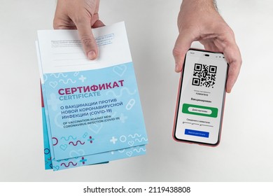 Russian state certificate of vaccination against COVID-19 and a smartphone with a valid QR code in the hands of a man. Cyrillic inscription 'CERTIFICATE', 'Vaccinated' and 'Valid'
