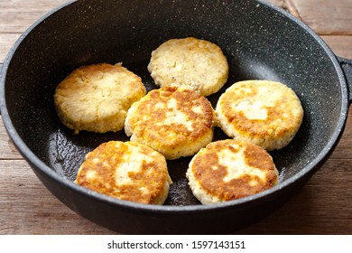 Russian traditional syrniki baked fried cottage cheese pancakes curd fritters breakfast on cast iron skillet on old wooden background view. Selective soft focus. Breakfast concept