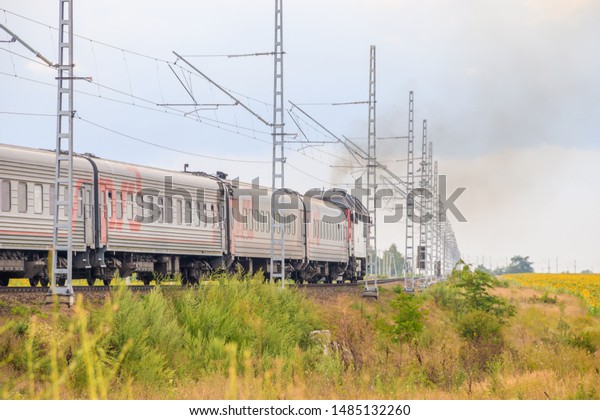 The Russian train travels by rail. Passenger train\
rides through the fields. Russian railway. locomotive. Russia,\
Anapa, July 16, 2019