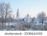 Russian winter, village landscapes with a temple in the background. Early morning. Snow, frost on trees and grass. Beautiful landscapes