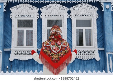 Russian Woman In Traditional National Pavlovo Posad Scarf, Shawl. Folk Style In Architectural Fashion, Architecture. Vintage Wooden Rural House, Ornamental Windows In Village In Ivanovo Region, Russia