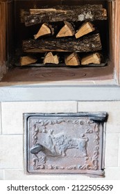 Russian Wood Stove. Close-up  Oak Firewood Stacked In Oven Dries. In Foreground At Top Is Firebox Door. Under It Is Ash Pan Door. 