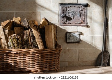 Russian Wood Stove. On Left Is Basket With Oak Firewood. In Foreground At Top Is Firebox Door. Under It Is Ash Pan Door