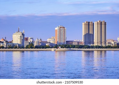 Russian-Chinese Border Along The Amur River. View From The Embankment Of The City Of Blagoveshchensk, Russia To The City Of Heihe, China. A Mixture Of Architectural Styles. The Time Of The Golden Hour