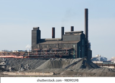 Rust Belt Steel Mill:   A Large Steel Manufacturing Plant Surrounded By Piles Of Coal And Coke Located In The American Rust Belt City Of Cleveland, Ohio