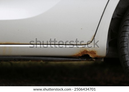 Rust on the side of a white car, close-up.