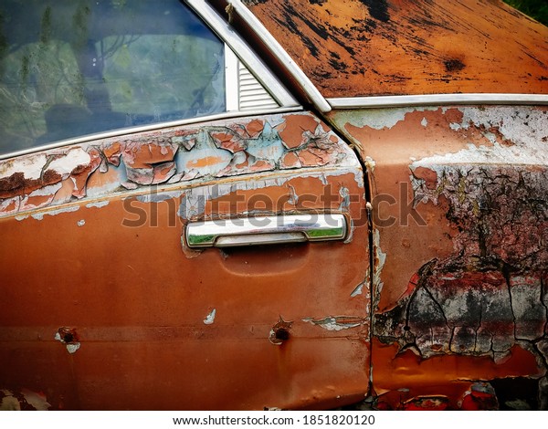 Rust on the side of white old car. Rust hole on\
old worn painted metal\
surface