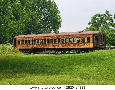Rust-covered abandoned train car with broken windows sitting on grassy ground surrounded by trees near Manns Choice, Pennsylvania, U.S.A