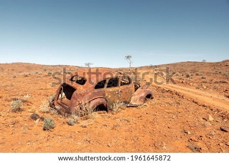 The rusted abandoned wreck of an old car in a remote area of Australian Outback on a rural dirt road near Fowlers Gap, NSW