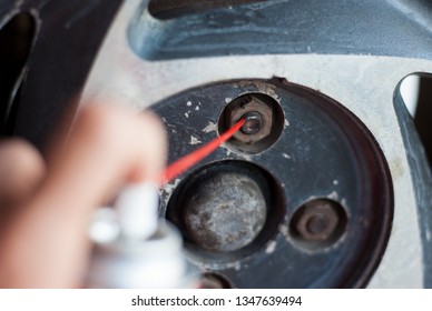 Rusted Car Wheel Nut. Rust Proof Oil Spray. Auto Mechanic Injects All-purpose Oil To Lubricate The Nut Thread Before Removing It.