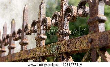 A rusted, decorated, wrought iron fence. Detail of an old retro iron fence made with decorated ironwork elements. Old and worn, still showing some of its former splendor 