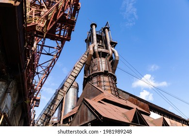 Rusted Exterior Of An Old Steel Mill Industrial Complex, Metal Shapes Against A Bright Blue Sky, Horizontal Aspect