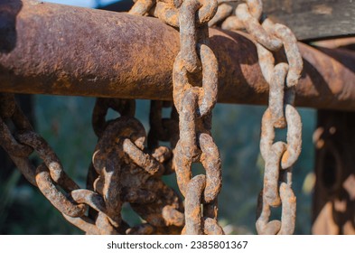 Rusted iron chains drape rod with dilapidated wood structure on an old defunct ranch at Chesebro Open Space in Agoura hills, Southern California. Strong depth-of-field with green blurry background.