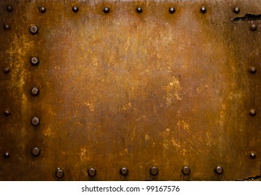 Rusted Metal Wall Plate With Three Borders Of Metal Studs, Showing Orange And Brown Scratch And Scuff Marks.  Suitable For Wallpaper Or Background Or Grunge Texture.