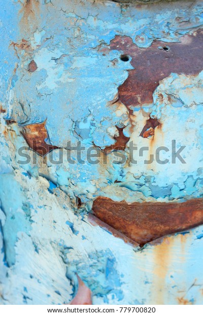 Rusted old blue metal surface. With\
peeling paint. Aged and weathered painted metal car.\
