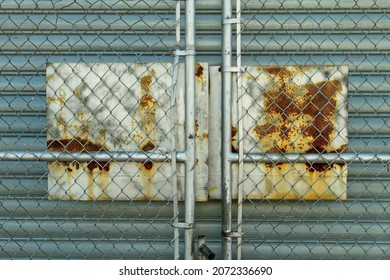 A Rusted Sign on a Fence