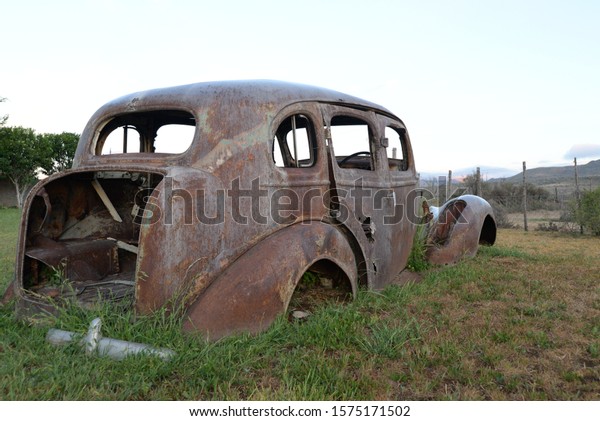 rusted vehicle wreckage on a\
a farm