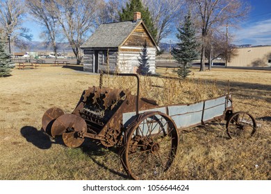 Rusted Wagon Wheel In Front Of Old Wild West Log Cabin In Mormon Pioneer Heritage Park, Scenic Highway 89 Near City Of Panguitch, Utah