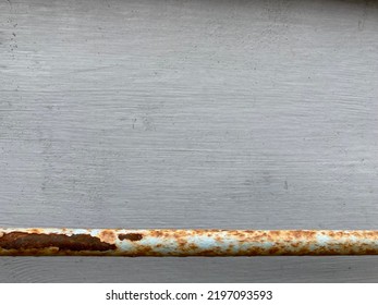 A Rusted Weathered Metal Bar In Front Of A Gray Painted Wooden Wall