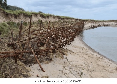 Rusted World War 2 era coastal defences at Gibraltar Point, Skegness, Lincolnshire.  Remains of anti-landing scaffolding, designed to hinder invasion by boat.  Beside tidal river.  October 2023. - Powered by Shutterstock