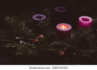 Rustic advent wreath with one candle lit in a dark room with copy space