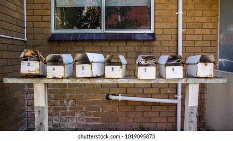 Rustic aged mailboxes in a row erected outside old residential units.