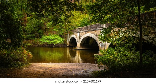 Rustic arching bridge with river in the forest at  East Rock Park in New Haven Connecticut
