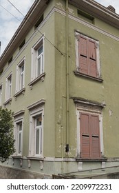 Rustic Architecture In Italy. Traditional Historic European Country Building. Aesthetic Summer Vacation Travel Concept. Wooden Windows, Shutters And Colourful Pastel Olive Walls