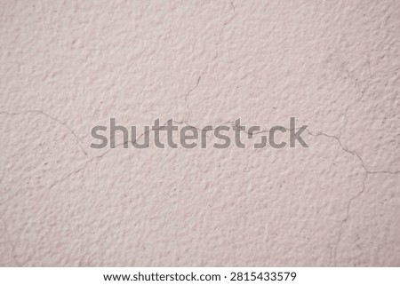 Rustic background texture of off-white painted wall with visible hairline cracks. Old building plaster degradation highlighting home inspection and masonry repair work.